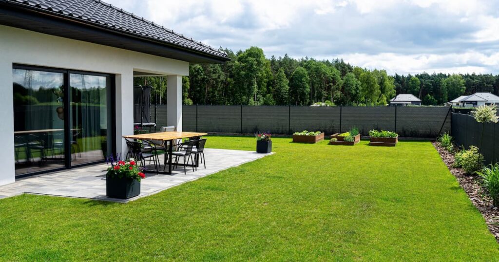 Une table moderne en bois brut recouverte de vernis de yacht, posée sur la terrasse du jardin avec clôture
