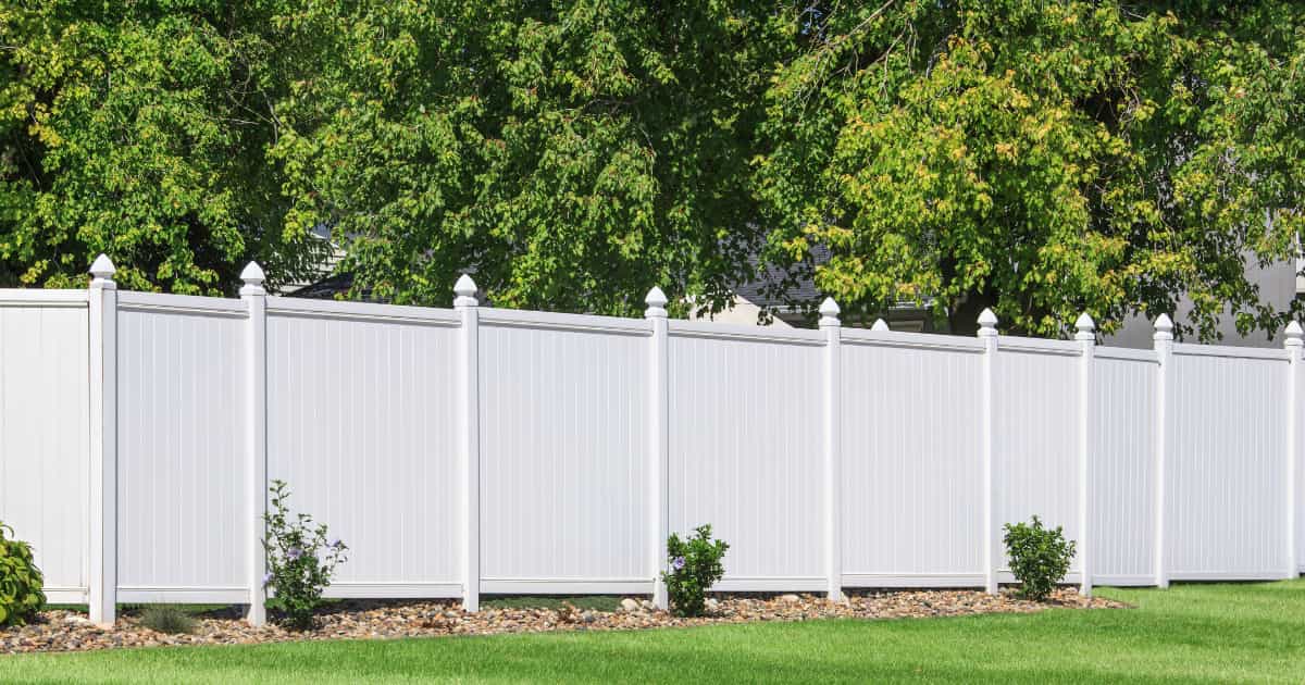 Palissade de jardin en PVC blanc devant des arbres